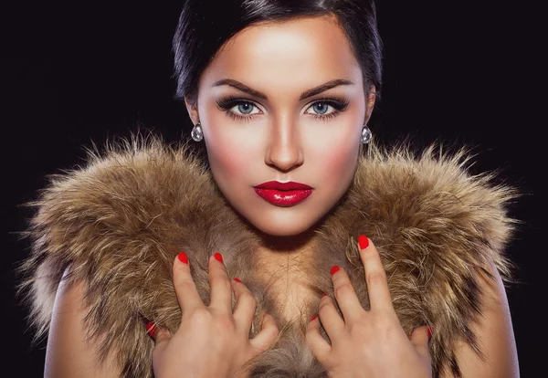 Beautiful brunette holding her hands on fur — Stock Photo, Image