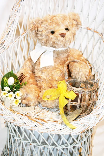 Lindo oso de peluche en una silla de mimbre blanco vintage con flores —  Fotos de Stock