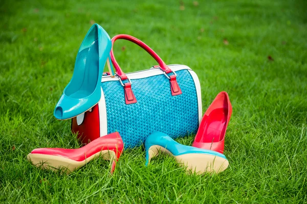 Due paia di scarpe verdi e rosse e borsa giacevano sull'erba — Foto Stock