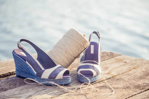 Sandálias de denim azul jazem na embreagem de madeira no lago — Fotografia de Stock