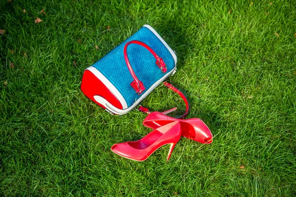 Boty a dámské kabelce ležela na trávě, dámská obuv — Stock fotografie