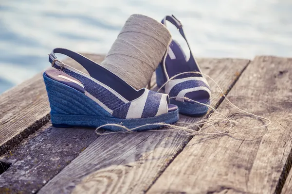 Džínové modré sandály leží na dřevěné spojky na jezeře — Stock fotografie
