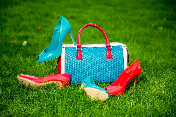 Dos pares de zapatos verdes y rojos y bolsa yacía en la hierba — Foto de Stock