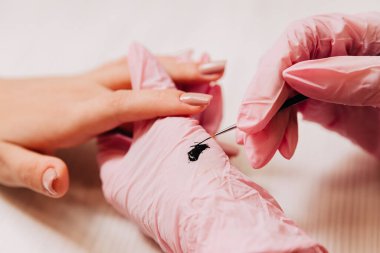 Manikür işlemi. Usta bir manikürcü, siyah cila ve ince bir fırça kullanarak yapay tırnaklar çizer..