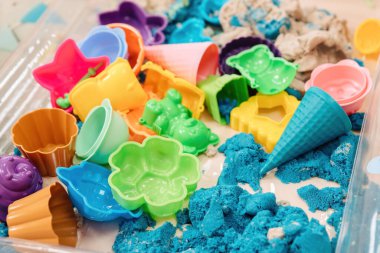 Farklı kum kalıplarının yanında çok renkli polimer kinetik kum.