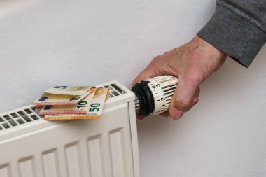 Erkek eli batarya sıcaklığı kontrolöründe, yakın plan. Isıtma için para.