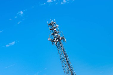 Telekomünikasyon kulesi açık bulutlu mavi gökyüzüne karşı. Anten yayınlanıyor.
