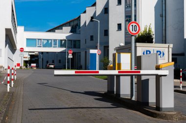 Bahçedeki paralı otoparka giden yolu kapatan bariyer. Beyaz idari bina.