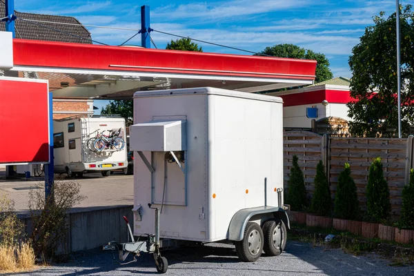 Trailer of a car standing next to a gas station. Summer sunny day.