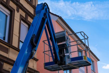 Binanın arka planında mavi asansör sepeti var. Mavi gökyüzü ve ışık bulutları.
