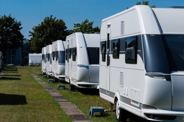 Yazın güneşli bir günde mavi gökyüzüyle ayakta duran bir dizi beyaz karavan..