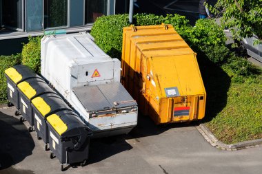 Evin bahçesinde duran çöp tenekeleri ve büyük konteynırlar. Yukarıdan görüntüle.