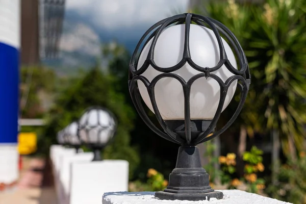 Close up of outdoor round lighting lantern framed in a metal. Focus in the foreground.