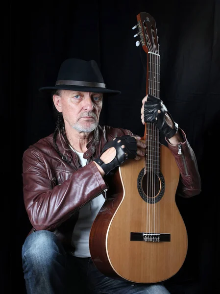 Siyah arka planda gitarlı şapkalı bir adam. Kendi portresi.