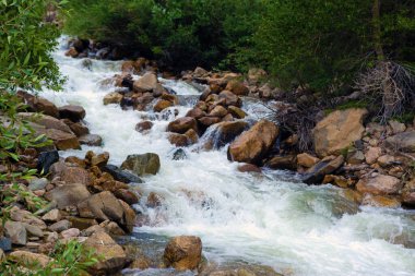 A view of one section of a rushing wild river loaded with granite rocks and boulders