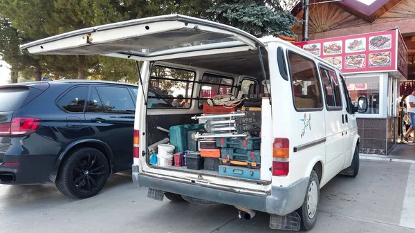 Aletlerle dolu bir minibüs sokağa park edilmiş. Açık havada çalışmak için inşaat ekipmanı ve elektrikli alet