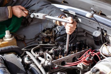 Tamirci eski motora silindir kafasını yerleştirmek için tork dinamometre anahtarı kullanıyor. Parçalanmış karbüratör motoru. DIY onarımı