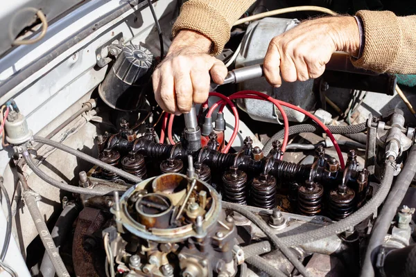 Mekanikern använder en momentnyckel för att reparera gasdistributionsmekanismen vid den gamla motorn. Demonterad förgasarmotor. DIY reparationscylinderhuvud med kamaxel Stockbild