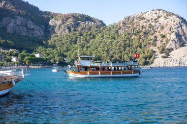 Deniz suyu taksi teknesi limana varıyor. Turunc adlı küçük bir turistik köyde dağlarla ve kayalarla çevrili bir sahil..