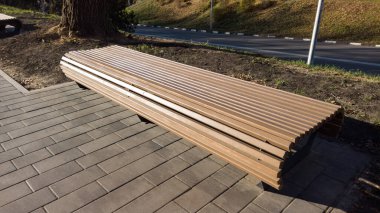 Güneşli bir günde şehir parkında arkası olmayan modern bir bank. Şehir gelişimi, şehir planlaması, kamusal alanlar. İnsanlar için rahat bir alan