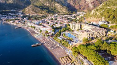 Türkiye 'nin Turunc kentindeki bir plajın hava görüntüsü. Güneşin doğuşu köyde İHA tarafından fotoğraflandı. Şemsiyeler ve güneş yatağı kumsalda.