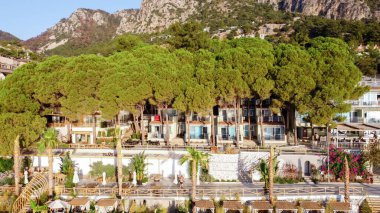 Türkiye 'nin Turunc tatil köyünde dikilmiş çam ağaçlarıyla birlikte turist otelinin hava manzarası. Denize giden ilk hattaki otel. Turizm beldesinde gezinti.