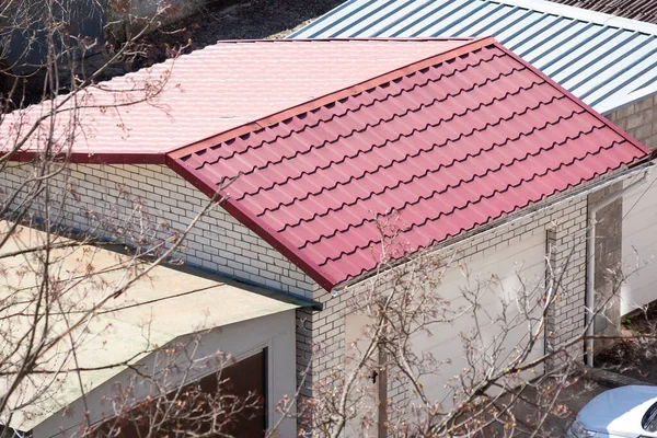 Metal roof tiles on garage. Brick garage in with red metal roof. Modern building materials — Stok fotoğraf