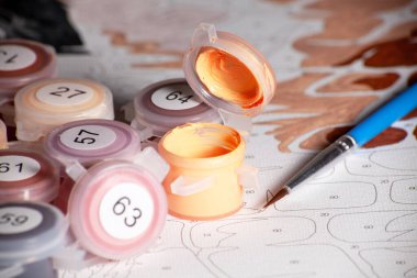 Kavanozu akrilik boya ve boya fırçasıyla açın. Sayılarla boyamak. Ev hobisindeki numaradan boyama. Kapatın. Kavanoz kapağına odaklan.