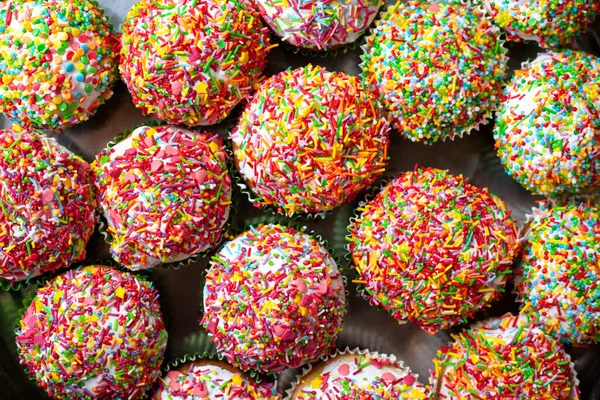 Ev yapımı kekler, şekerli süslemeler. Bir grup ev yapımı vanilyalı kek. Beyaz, çok renkli dekorasyon. Tatlı kek arkaplanı.