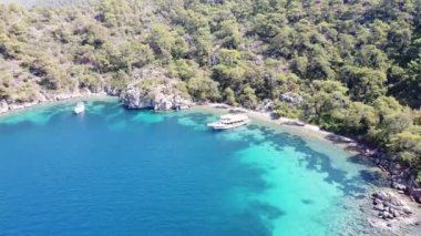 Kum kıyısı ve turkuaz su ile adanın yakınındaki mavi denizdeki yatın havadan görüntüsü. Türkiye 'de turistik tekne gezisi.