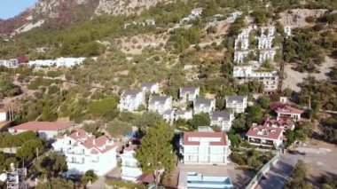 Çatıda mavi parlak güneş enerjili voltaik panelleri olan modern ev kulübelerinin havadan görünüşü. Yeşil enerji sistemli dağ köyü