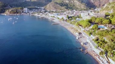 Turunc adlı küçük bir turistik köyde dağlarla ve kayalarla çevrili bir sahil. Sakin sulara demirlemiş tekneli deniz manzarası.