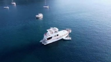 Aerial video movement around Of White Moored Luxury Boat In sea bay, Drone view of pleasure yachts in calm blue water near resort town. Turkey, Turunc, Marmaris - September 10, 2021