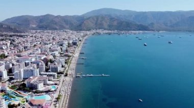 Marmaris 'teki küçük bir tatil köyünde yat limanı ve Sea Bay. Su üzerinde hareket eden bir sürü tekne ve gemiyle deniz manzarası. Drone görünümü.