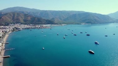 Marmaris 'teki küçük bir tatil köyünde yat limanı ve Sea Bay. Su üzerinde hareket eden bir sürü tekne ve gemiyle deniz manzarası. Drone görünümü.