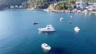White Moored Boats and Yacht in sea Bay 'in etrafındaki hava video hareketleri, tatil köyü yakınlarındaki sakin mavi sulardaki zevk gemilerinin drone görüntüsü. Türkiye, Turunc, Marmaris - 10 Eylül 2021