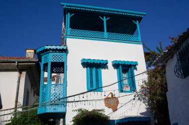 Türkiye 'nin eski Marmaris kentinde güneşli bir günde çiçek ve bitkilerle dolu güzel dar bir cadde. Mavi balkon ve taş kaldırımları ve duvarları olan sokak kapısı. Marmaris, Türkiye - 8 Eylül 2021.