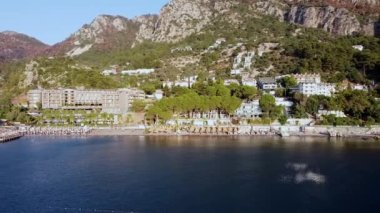 Türkiye 'nin Turunc tatil köyündeki sahil ve sahil manzaralı panoramik insansız hava aracı. Deniz manzaralı bir tatil köyü. Dağlarla çevrili bir tatil köyü.