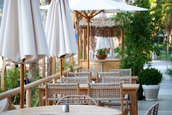Street cafe on the promenade in resort town. Empty tables and chairs in outdoor restaurant. Summer seasoal cafe. Selective focus.