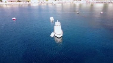 White Moored Luxury Boat 'un deniz koyundaki hava hareketliliği tatil köyü yakınlarındaki sakin mavi sularda keyif yatlarının insansız hava aracı görüntüsü. Türkiye, Turunc, Marmaris - 10 Eylül 2021