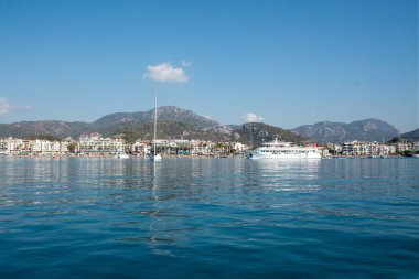 Big white pleasure ship cruises near Marmaris city in Turkey. Big white boat yacht against of the resort city. Ships in sea. Sea traveling. View from boat. Marmaris, Turkey - September 8, 2022.