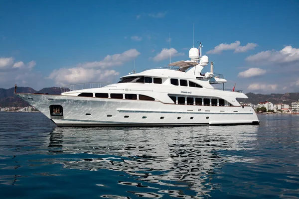 Big white modern yacht moored near Marmaris city in Turkey. Luxury white boat yacht against of the resort city. Ships in sea. Sea traveling. View from boat. Marmaris, Turkey - September 8, 2022.