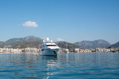 White modern yacht moored near Marmaris city in Turkey. Luxury white boat yacht on the background of the resort city. Ships in sea. Sea traveling. View from boat. Marmaris, Turkey - September 8, 2022.