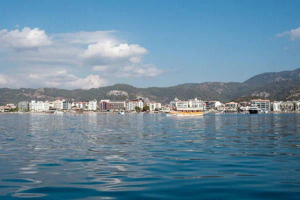 Pleasure ship cruises near Marmaris city in Turkey. Big boat against of the resort city. Ships in sea. Sea traveling. View from boat. Marmaris, Turkey - September 8, 2022.