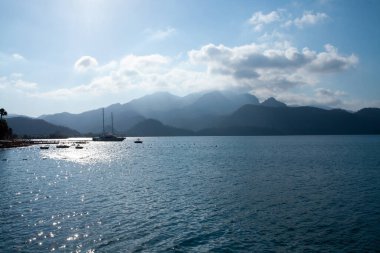 Summer seascape beautiful waves, blue sea water in sunny day. Sea bay with far hazed mountains on horizon. Fog in the mountains.