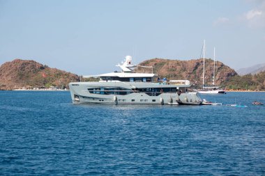 Big white modern yacht moored in Aegean sea near Turkey coast. Luxury white boat yacht against of the resort city. Ships in sea. Sea traveling. View from boat. Marmaris, Turkey - September 9, 2022.