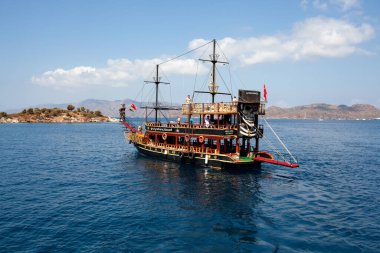 Pleasure yacht in the sea. Tourist ship with people on board with turkish flag sails on the waves. Fast moving excursion ship boat. Marmaris, Turkey - September 9, 202