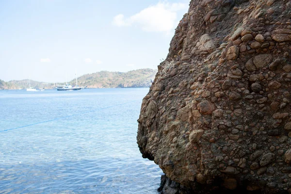 Stone cliff in Aegean sea. High rock in the sea. View from sea. Rock reflection in blue water sea
