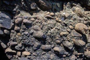 Kaba desenli yüzeyi olan doğal bir taş zemin. Deniz taşı dokusu. Yakın plan. Bulanık ve odaklanmış arkaplan