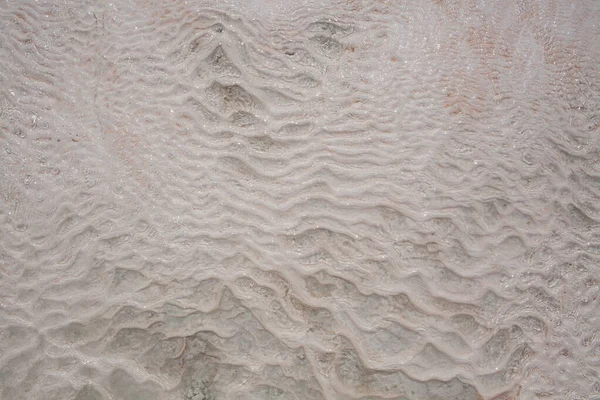 トルコのパムッカレカルシウムトラバーチンの水と石灰岩の床 非対称パターンのクローズアップ 白い波状の質感 ホワイトカルシウム石の質感 石灰岩だ 専用画像 — ストック写真